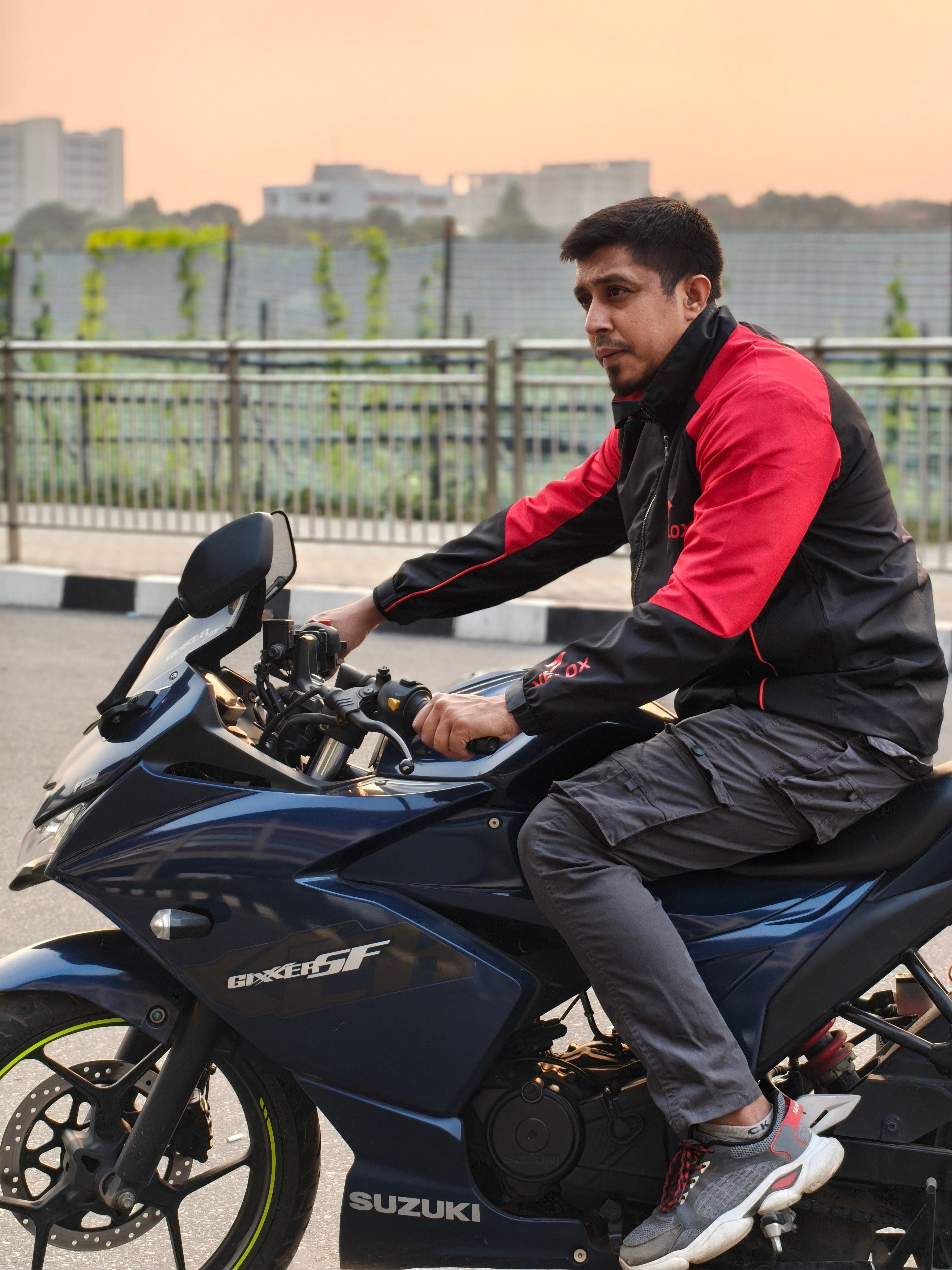 Person sitting on a Suzuki motorcycle with a cityscape in the background